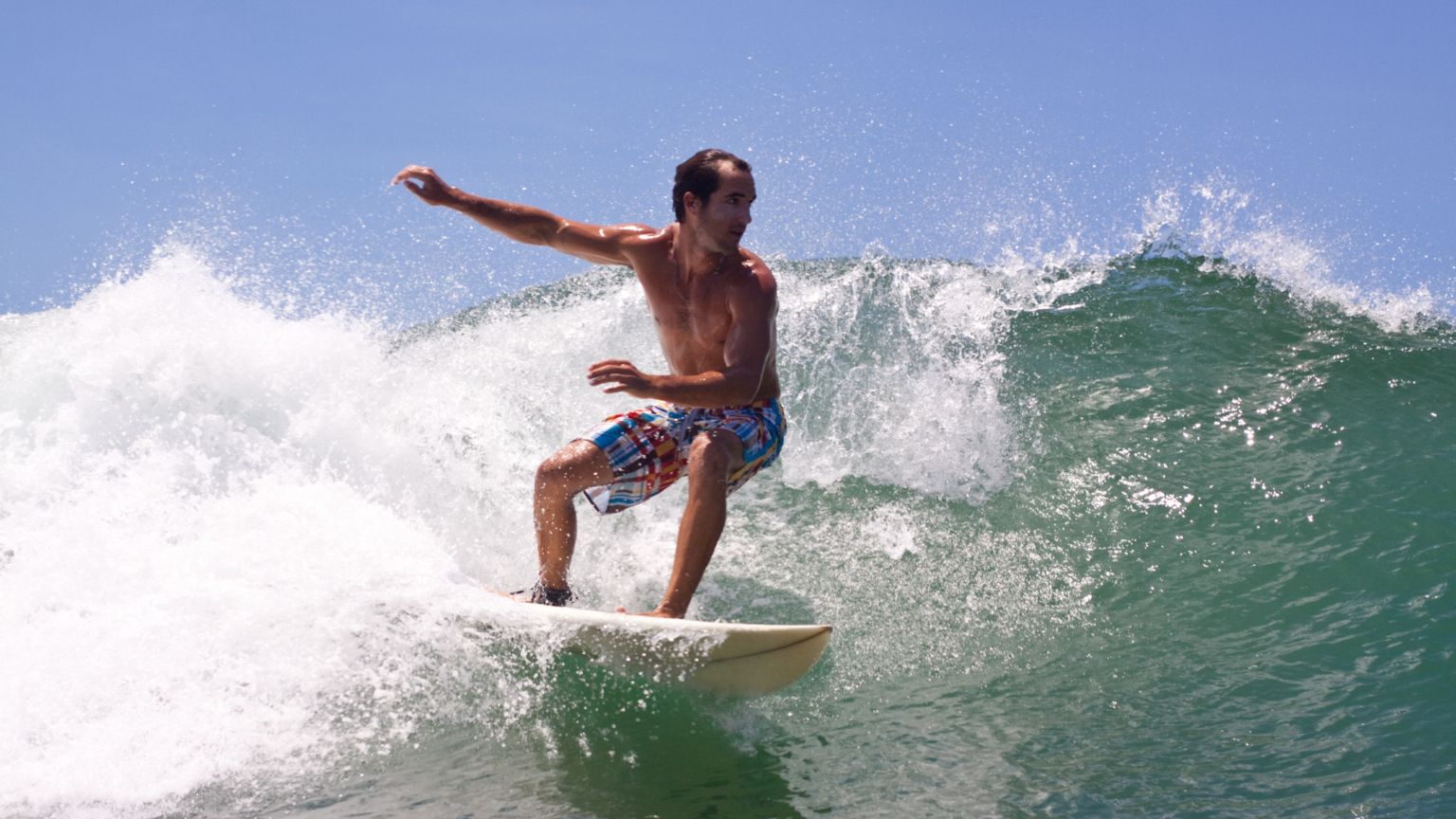 Solo traveler learning to surf in Santa Teresa with gentle waves and tropical beach in the background.