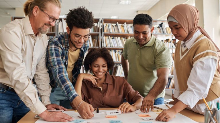 Group of diverse students collaborating in a library while learning and practising english together in a supportive environment.