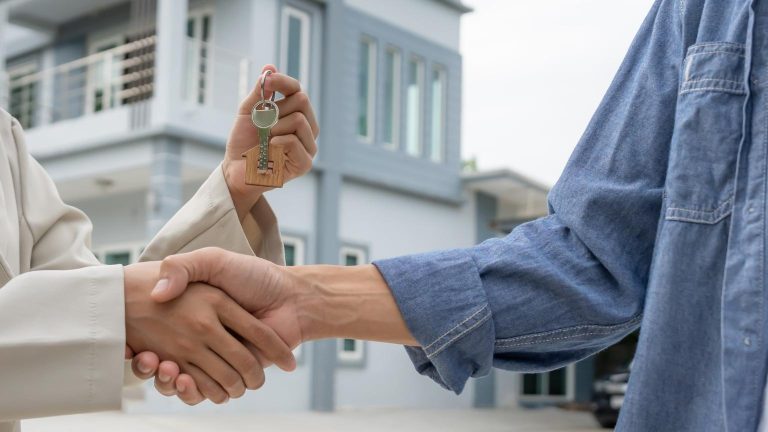 Property management agreement symbolized by key handover in front of a residential property