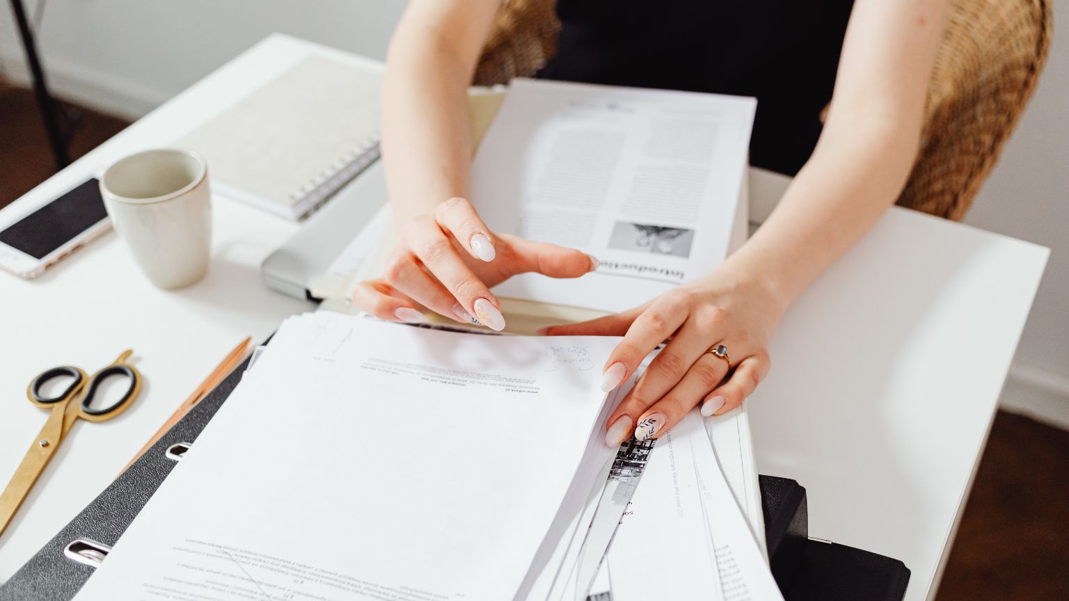 Hands organizing legal documents on a desk, representing strategic immigration planning and legal decision-making.