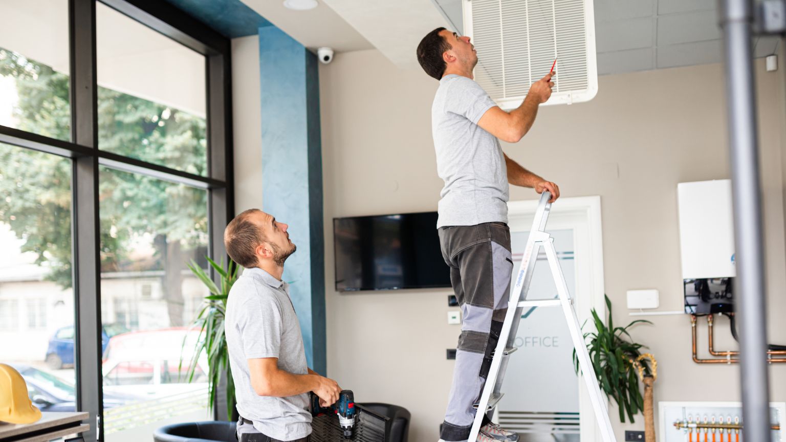 property maintenance technicians inspecting and servicing indoor air conditioning system in a holiday home